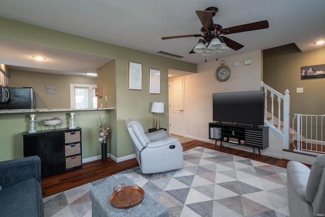 living room with ceiling fan, hardwood / wood-style floors, and a textured ceiling