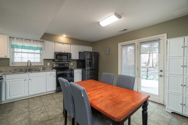 kitchen featuring white cabinetry, sink, light stone counters, black appliances, and a textured ceiling