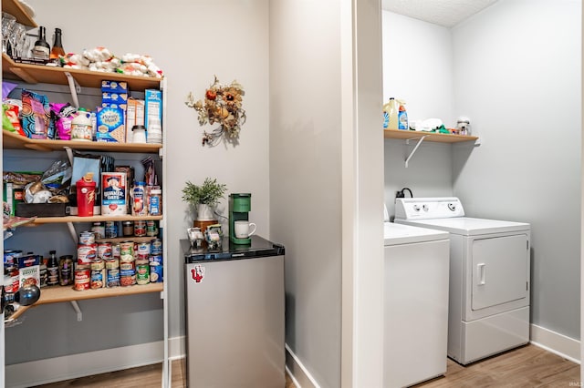 clothes washing area with separate washer and dryer and light wood-type flooring