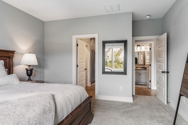 carpeted bedroom with connected bathroom and sink