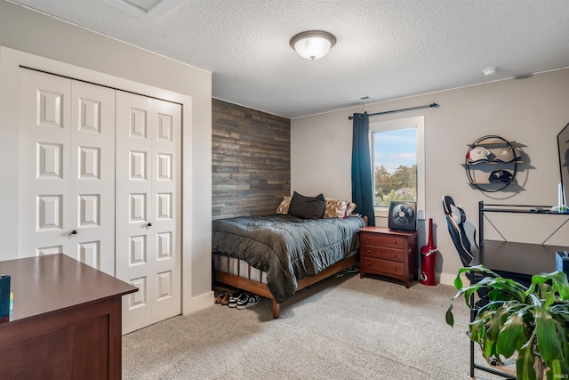 carpeted bedroom featuring a closet, wooden walls, and a textured ceiling