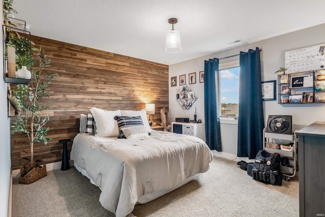 bedroom featuring carpet floors, a textured ceiling, and wood walls