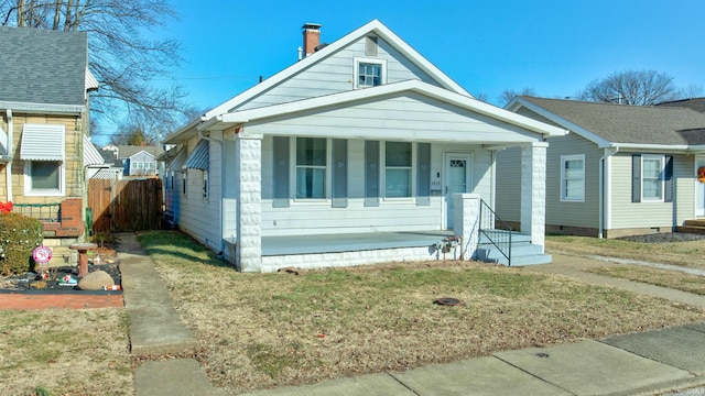 bungalow-style home with a front yard and covered porch