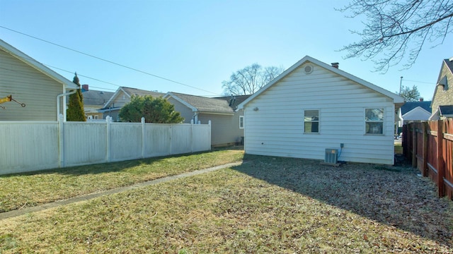 rear view of property featuring central AC unit and a lawn