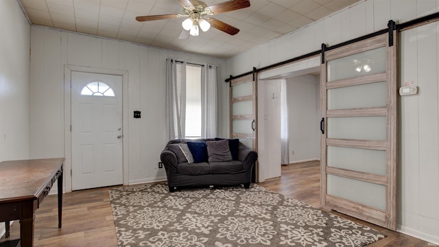 foyer with light hardwood / wood-style flooring, a barn door, and ceiling fan