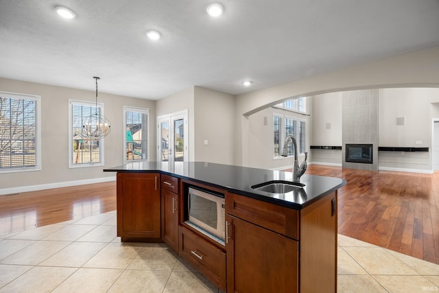 kitchen with pendant lighting, sink, light tile patterned floors, and an island with sink