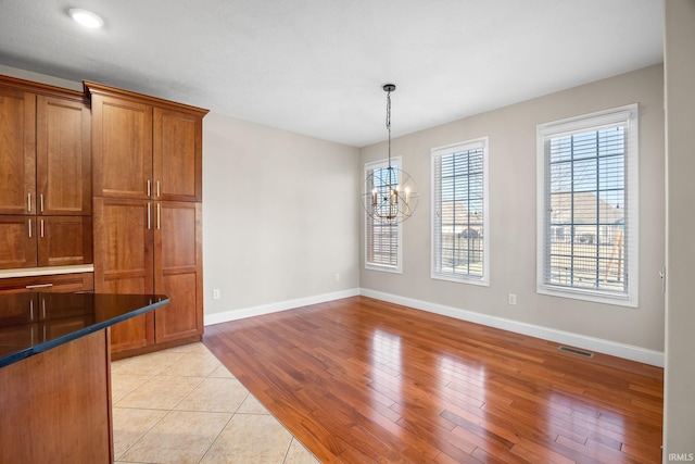 unfurnished dining area with a chandelier and light wood-type flooring