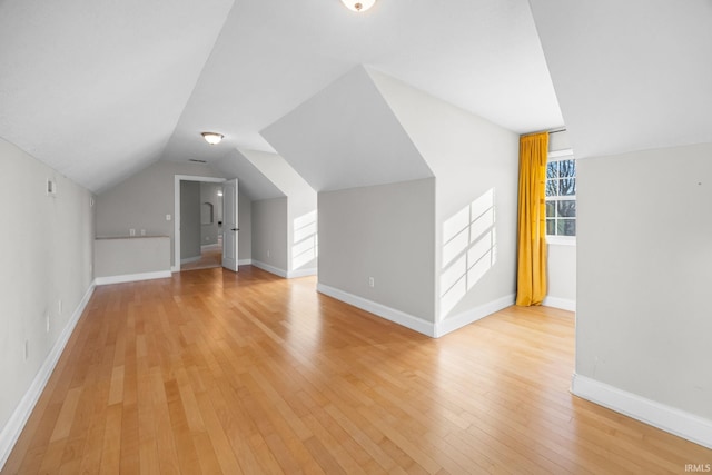 additional living space featuring vaulted ceiling and light hardwood / wood-style floors