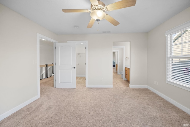 unfurnished bedroom featuring ensuite bathroom, a spacious closet, ceiling fan, light carpet, and a closet