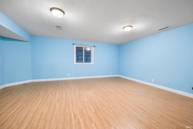 spare room with a textured ceiling and light hardwood / wood-style flooring