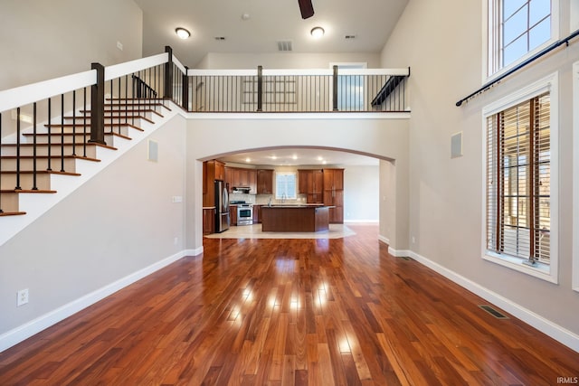 unfurnished living room with a high ceiling, dark hardwood / wood-style floors, sink, and ceiling fan