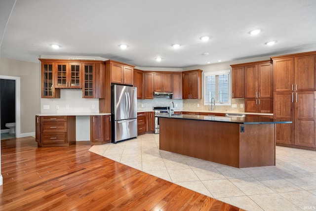 kitchen featuring stainless steel appliances, a center island, decorative backsplash, and light hardwood / wood-style flooring