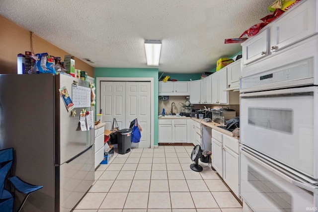 kitchen featuring sink, white double oven, white cabinets, and refrigerator