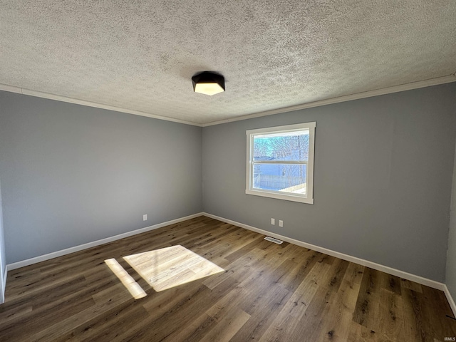 empty room featuring dark wood-type flooring, ornamental molding, and a textured ceiling