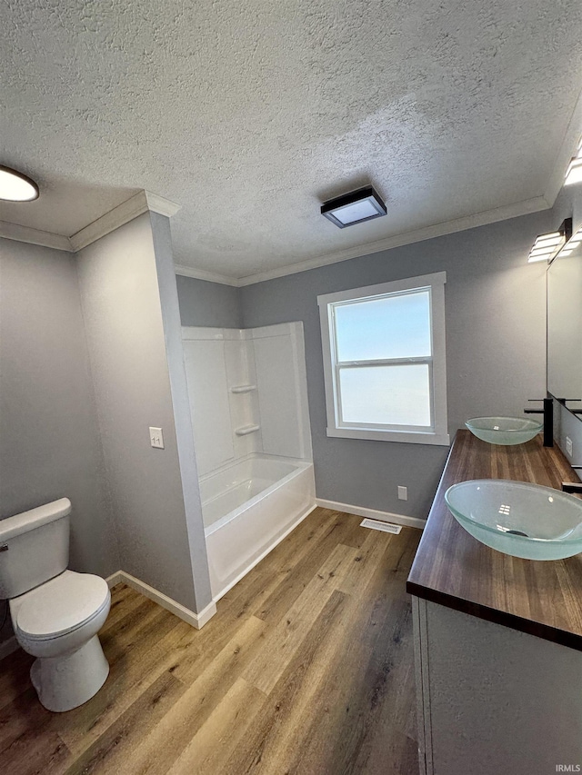 full bathroom with hardwood / wood-style flooring, vanity, ornamental molding, a textured ceiling, and toilet