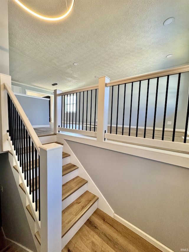 stairs featuring hardwood / wood-style flooring and a textured ceiling