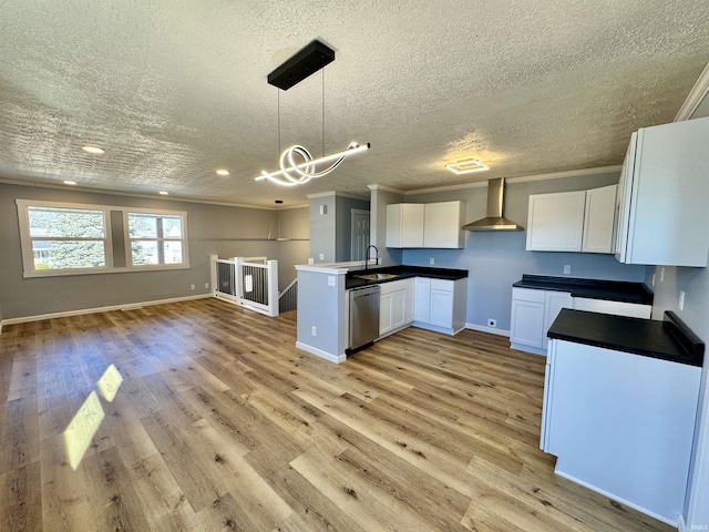 kitchen featuring pendant lighting, wall chimney range hood, light hardwood / wood-style flooring, white cabinetry, and stainless steel dishwasher