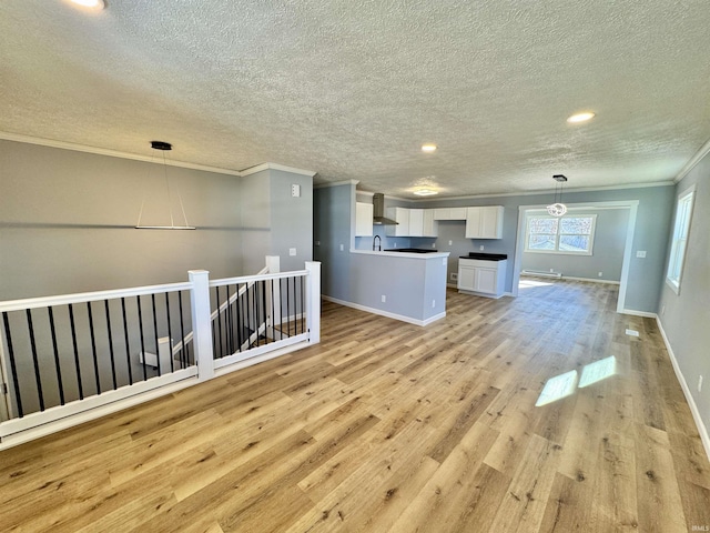 unfurnished living room with crown molding, sink, light hardwood / wood-style flooring, and a textured ceiling