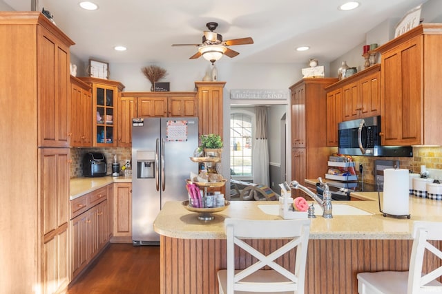 kitchen featuring a breakfast bar, appliances with stainless steel finishes, dark hardwood / wood-style flooring, kitchen peninsula, and decorative backsplash