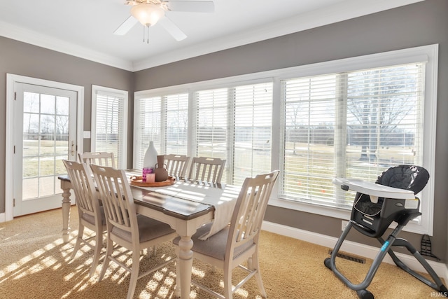 dining space featuring crown molding, plenty of natural light, light colored carpet, and ceiling fan