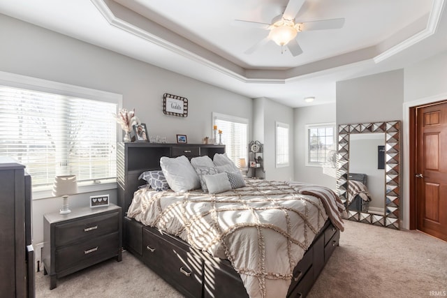 carpeted bedroom with a raised ceiling and ceiling fan