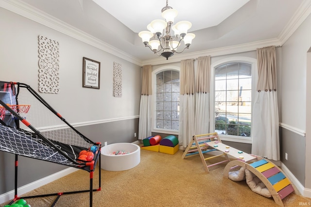 rec room with carpet floors, ornamental molding, a raised ceiling, and a chandelier