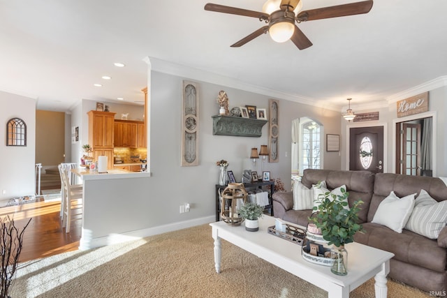 living room with crown molding, light colored carpet, and ceiling fan