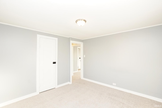 empty room featuring ornamental molding and light carpet