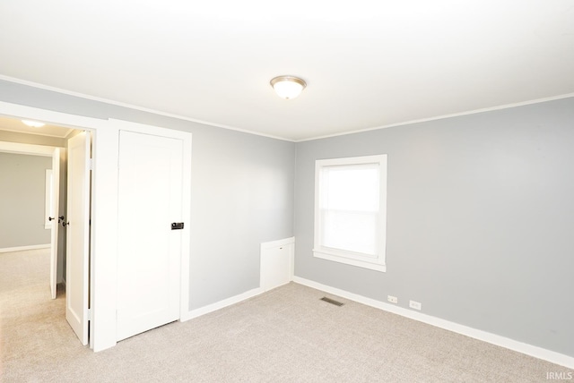 carpeted spare room featuring crown molding