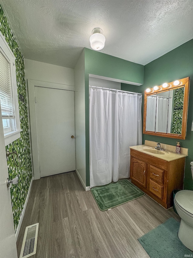 bathroom featuring vanity, wood-type flooring, a textured ceiling, curtained shower, and toilet