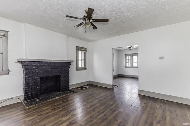 unfurnished living room featuring dark hardwood / wood-style flooring, a brick fireplace, a textured ceiling, and ceiling fan