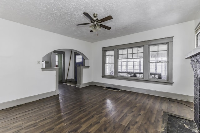 unfurnished living room with ceiling fan, dark hardwood / wood-style floors, and a textured ceiling