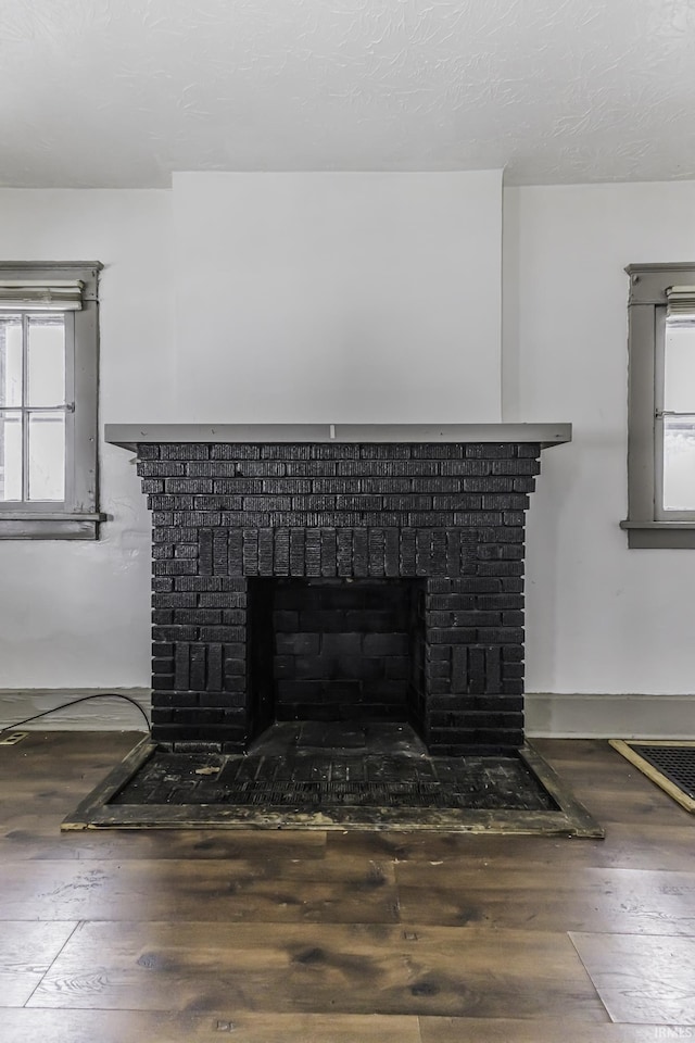 interior details featuring a brick fireplace, hardwood / wood-style floors, and a textured ceiling