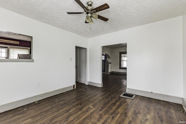 empty room with a textured ceiling, dark hardwood / wood-style floors, and ceiling fan