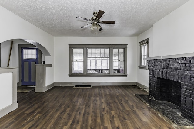 unfurnished living room with a textured ceiling, a fireplace, dark hardwood / wood-style floors, and ceiling fan