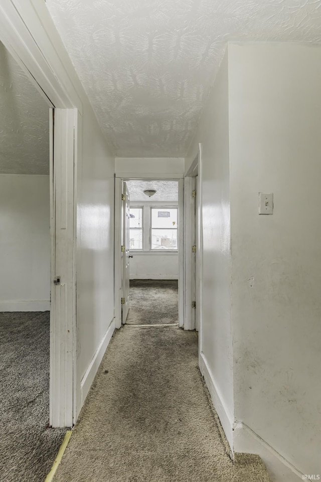 hall featuring a textured ceiling and carpet flooring