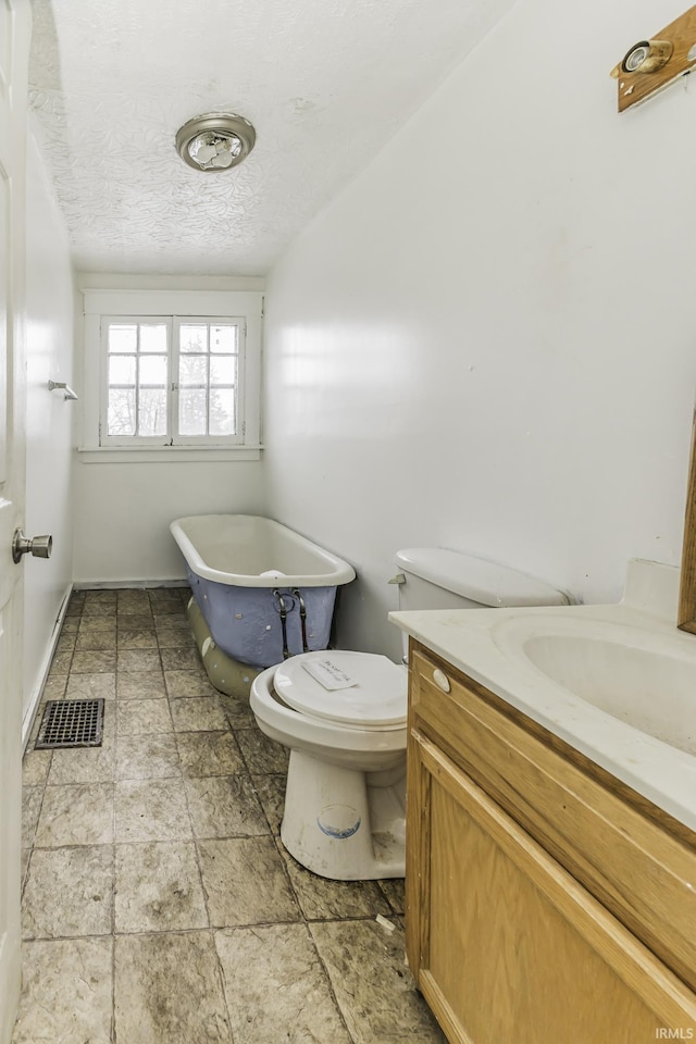 bathroom with vanity, toilet, a textured ceiling, and a washtub