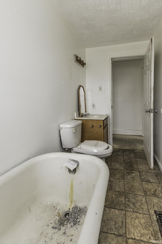 bathroom featuring a tub, a textured ceiling, and toilet