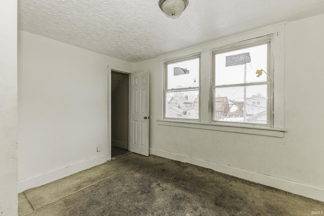 carpeted empty room with a textured ceiling