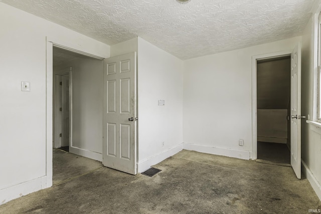 spare room with dark colored carpet and a textured ceiling