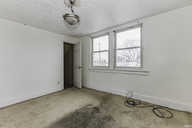 spare room with light colored carpet and a textured ceiling