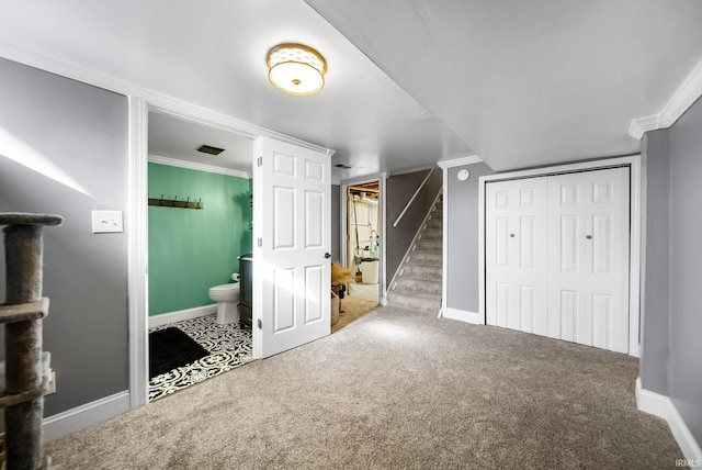 unfurnished bedroom with ornamental molding, carpet, ensuite bath, and a closet