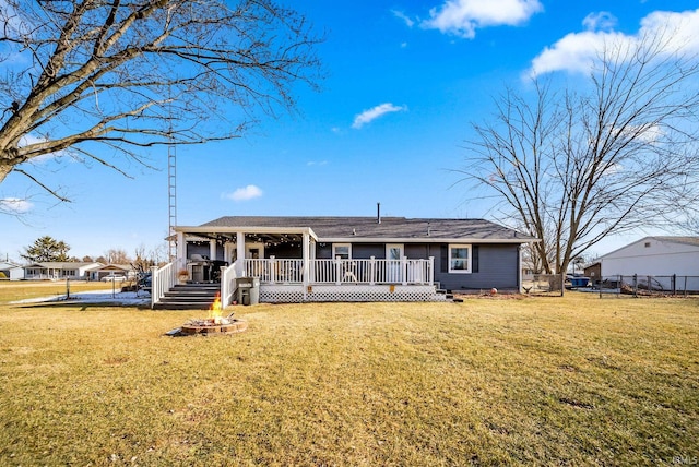 back of property with a yard, covered porch, and an outdoor fire pit