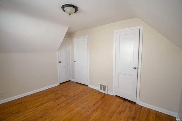 bonus room with lofted ceiling and light wood-type flooring