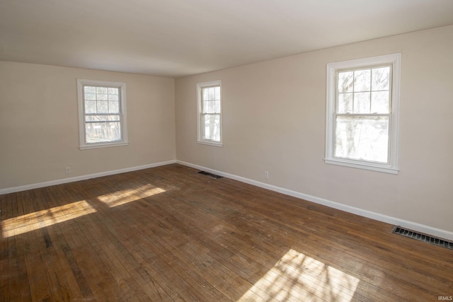 empty room featuring a wealth of natural light and dark wood-type flooring