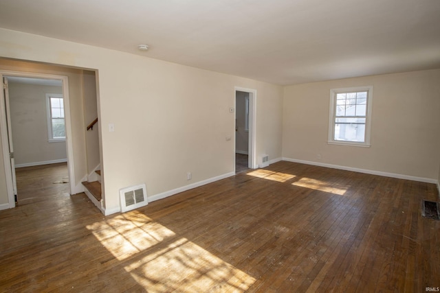 spare room featuring a healthy amount of sunlight and dark wood-type flooring