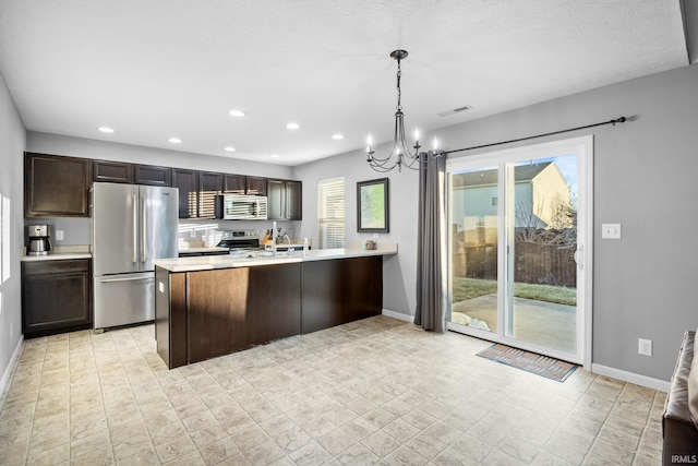 kitchen featuring pendant lighting, dark brown cabinetry, appliances with stainless steel finishes, and an inviting chandelier