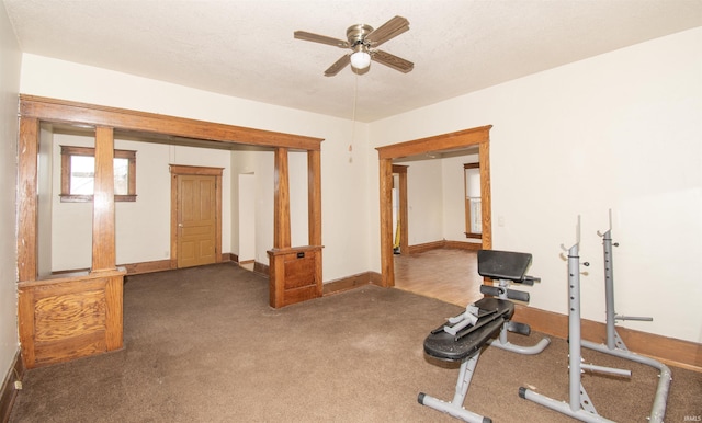 workout area with ceiling fan and dark carpet