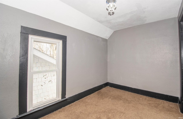 unfurnished room featuring lofted ceiling and carpet flooring