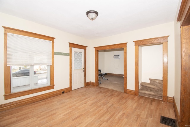 unfurnished room with a wall unit AC and light wood-type flooring